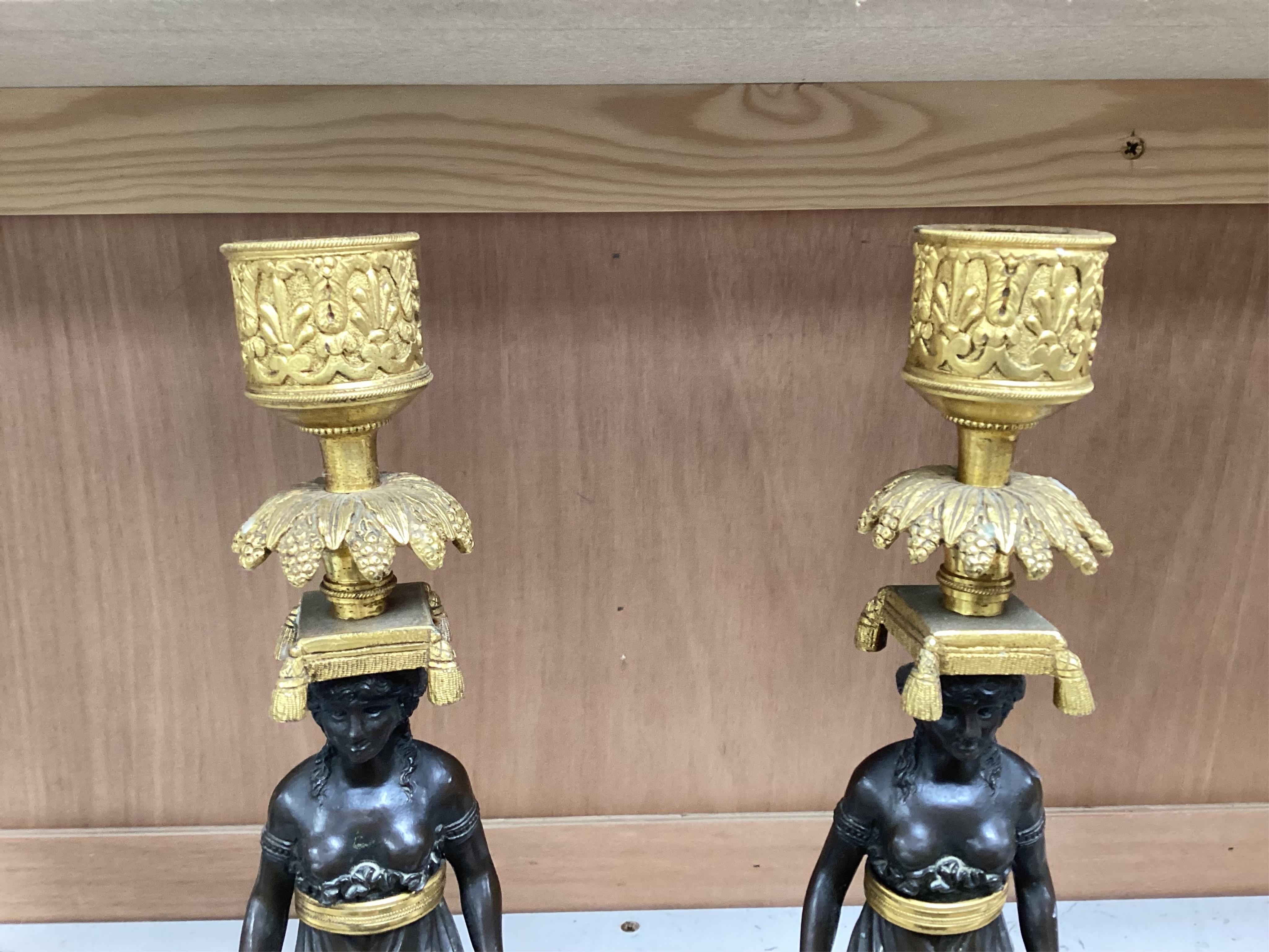 A pair of Regency bronze and gilt candlesticks in the form of standing classical figures mounted on marble bases, 31.5cm high.